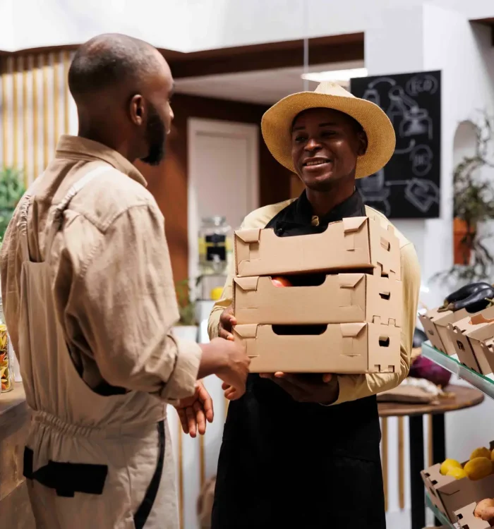 Smiling African American man, the owner of modern supermarket, offers a variety of eco friendly organic products. The shelves are filled with fresh produce, glass jars and reusable packaging options.